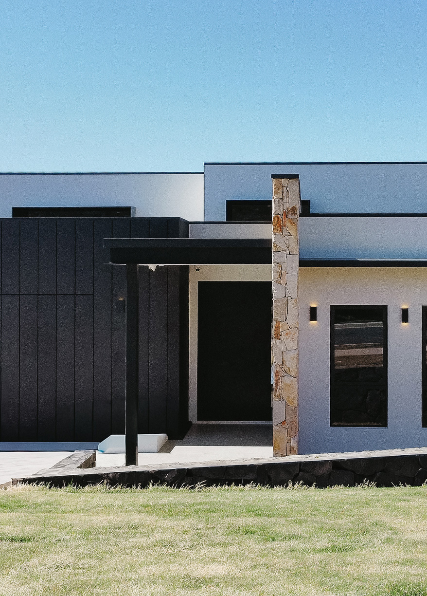 Contemporary home entrance with dark cladding and stone feature column