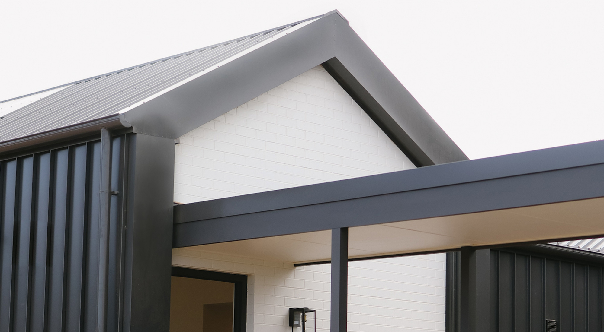 Modern home exterior with pitched roof and dark vertical cladding.
