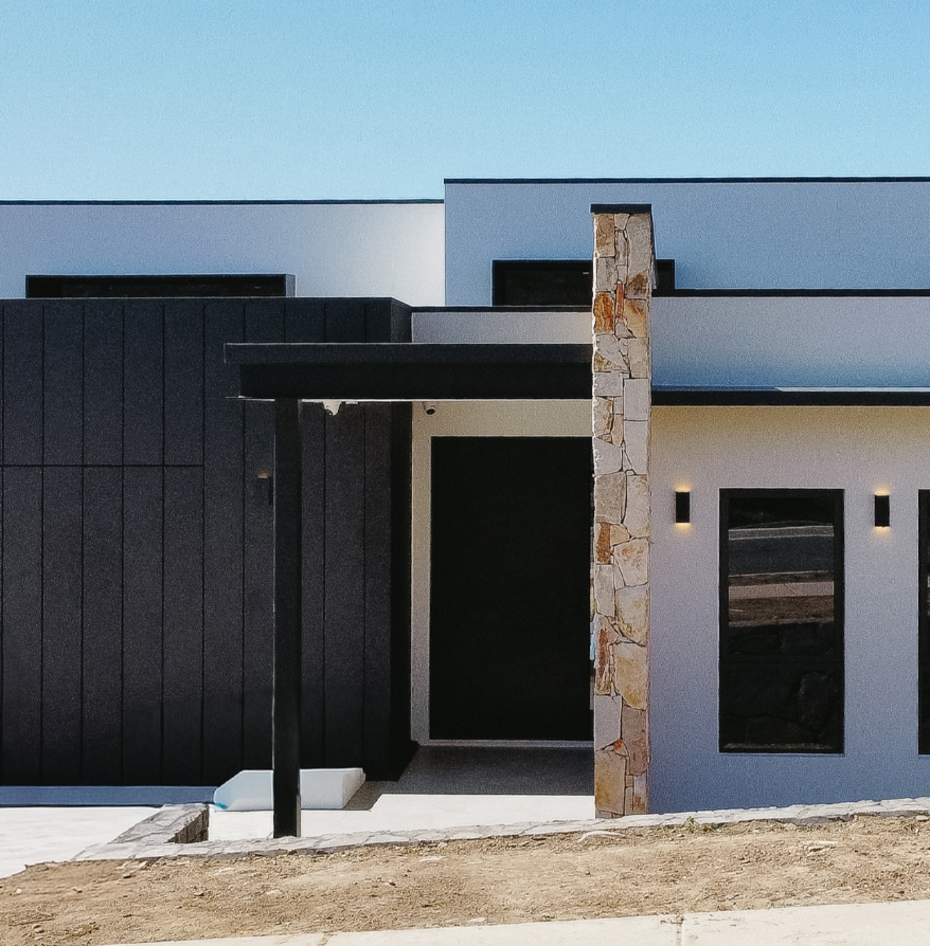Contemporary home entrance with dark cladding and stone feature column.