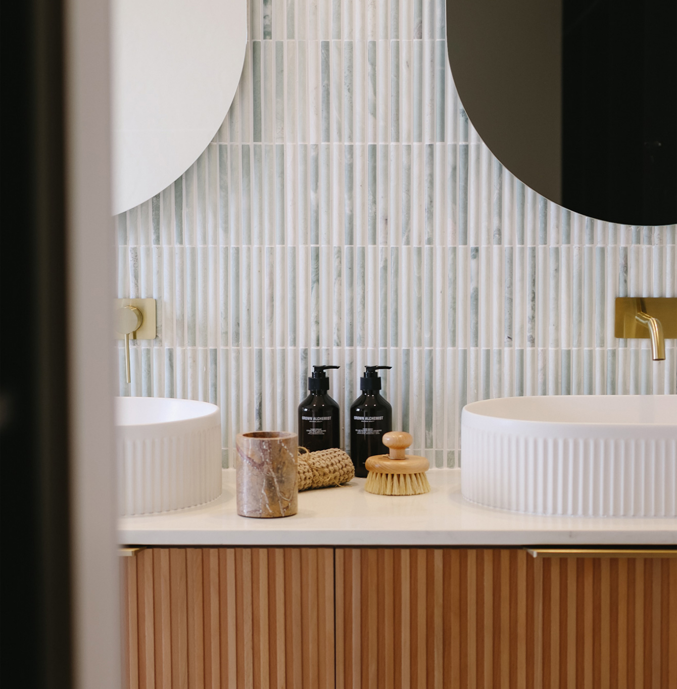 Modern bathroom vanity with timber cabinetry, round mirrors and tiled splashback