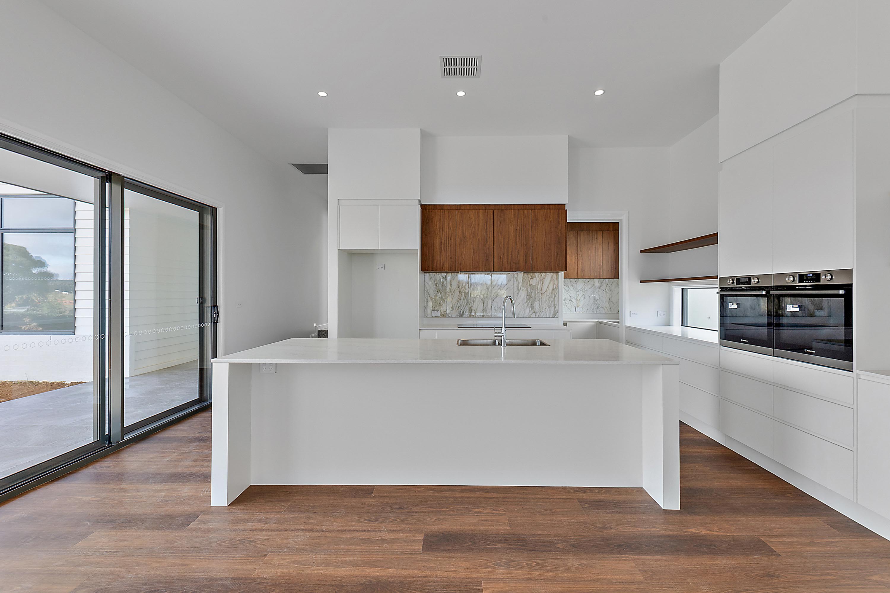 Modern white kitchen with large island, timber accents and integrated appliances, 14 Blakelys Close Project, Sutton ACT